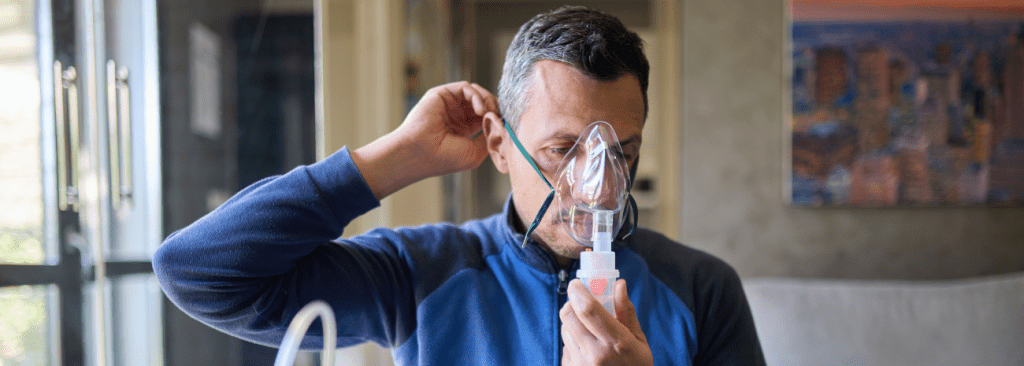 Man sitting at the table and putting on an oxygen mask