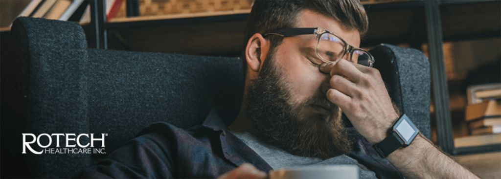 Man rubbing his eyes behind his glasses from tiredness